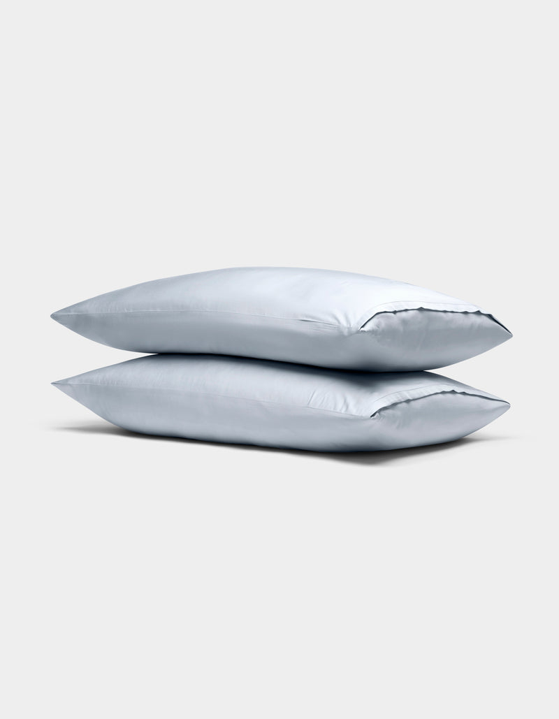 Two Cozy Earth Bamboo Pillowcases in light gray are stacked neatly against a plain, light gray background.