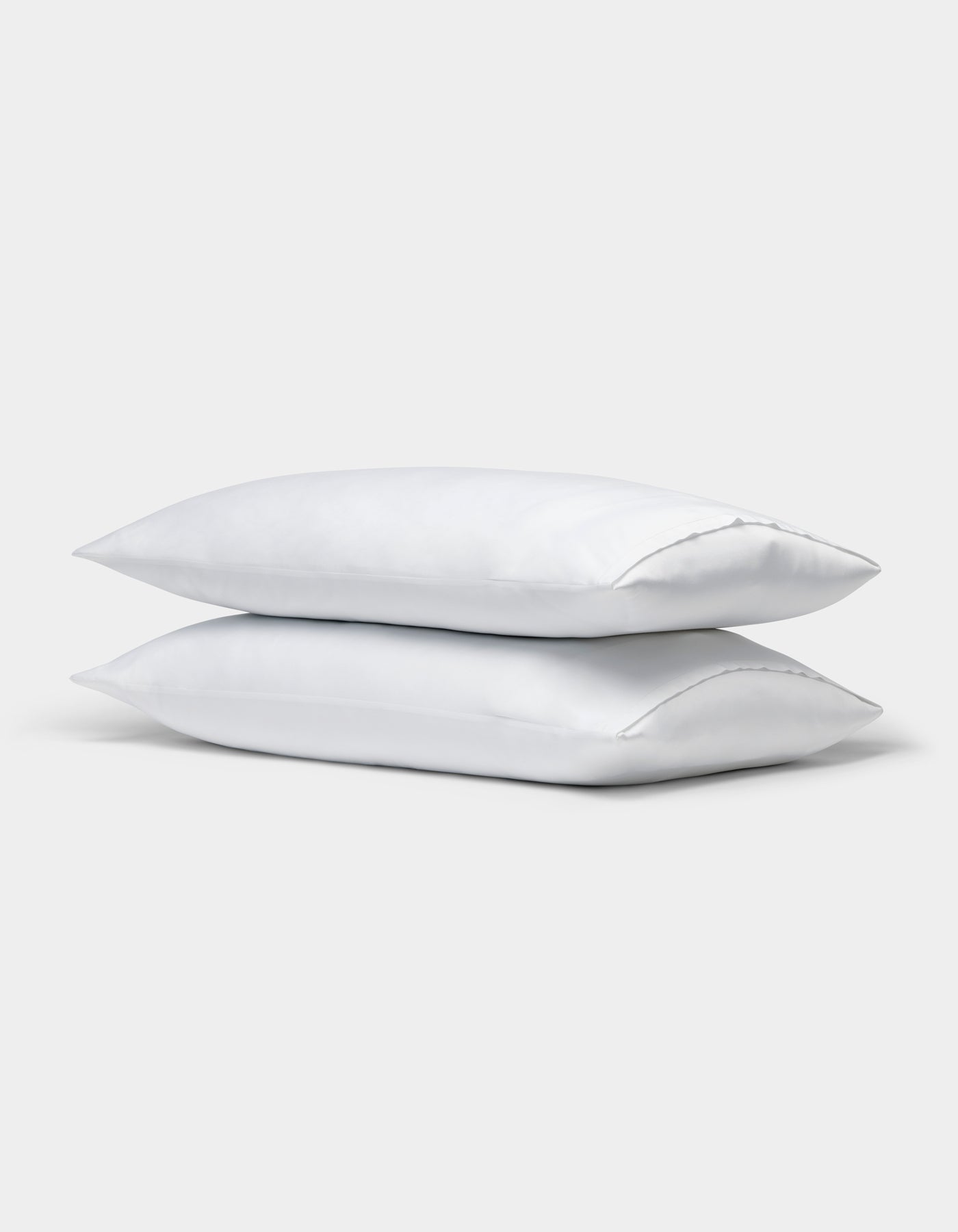 Two Cozy Earth Bamboo Pillowcases, plain white, are stacked on top of each other against a light gray background. 