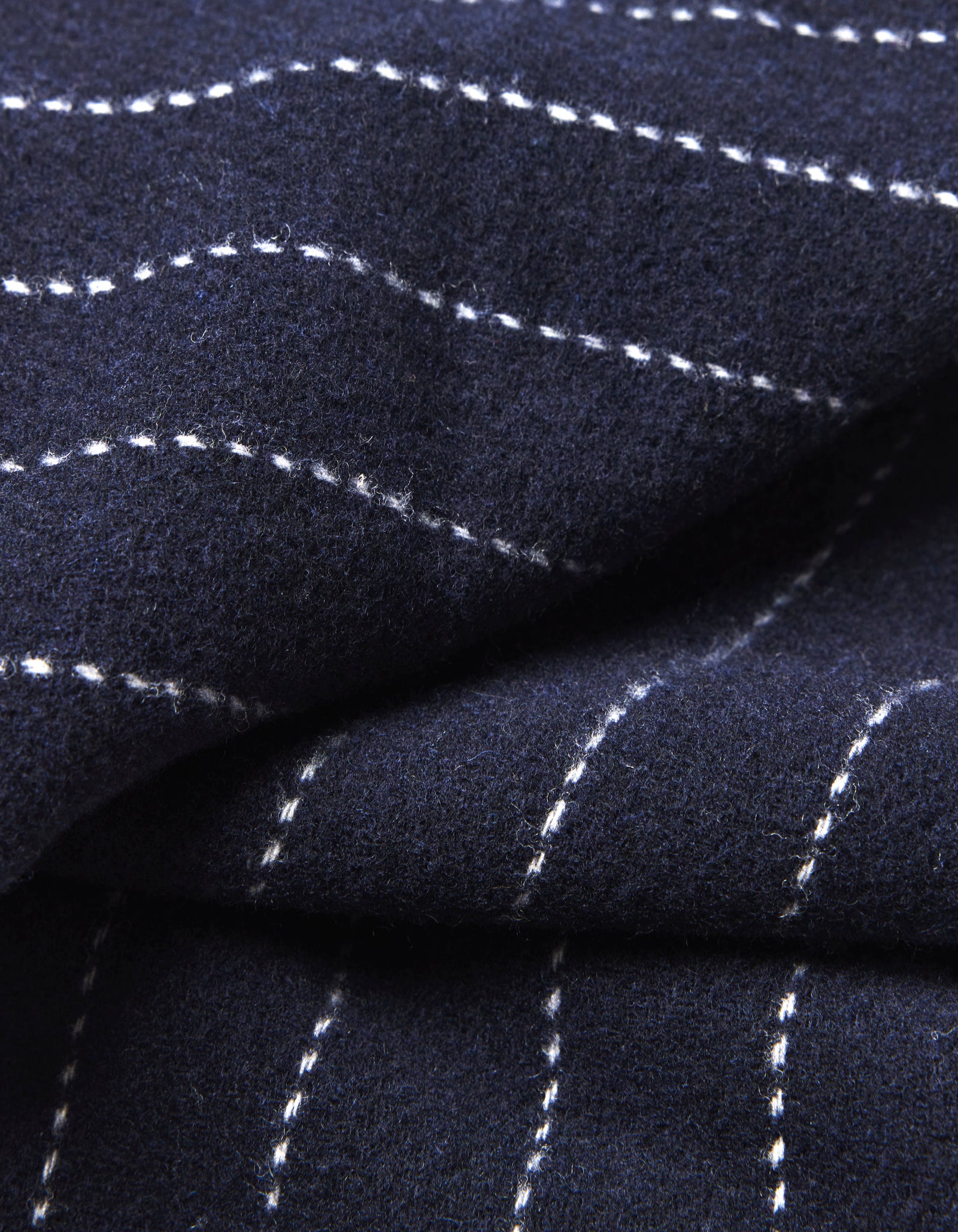 Close-up of Cozy Earth's Florence Throw: dark blue fabric with white dashed stitching forming a grid pattern. The material looks soft with gentle folds and textured detailing.