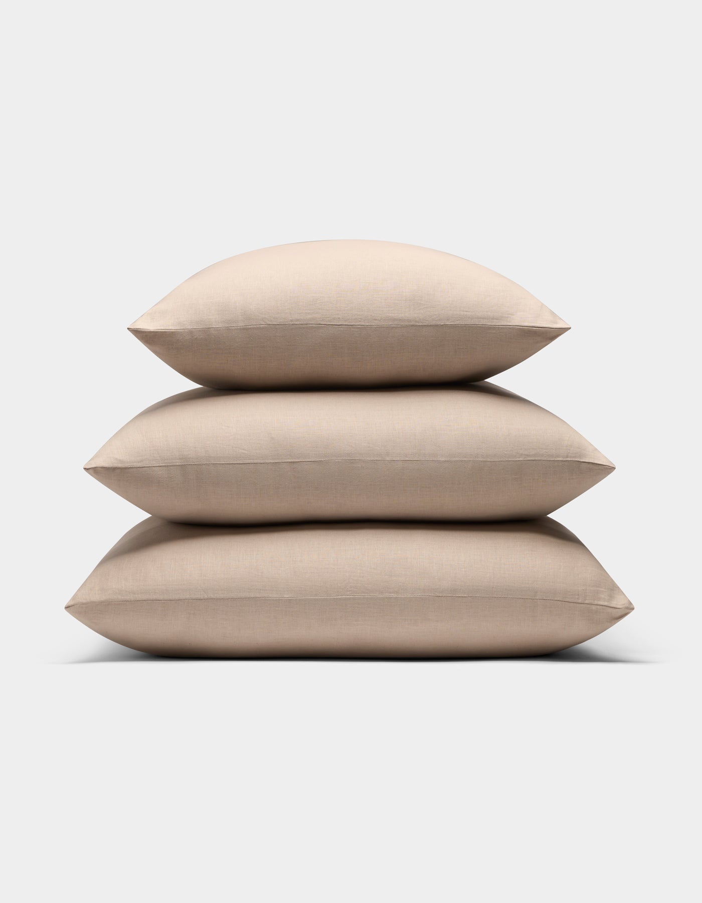 Three Cozy Earth Linen Throw Pillows are stacked neatly on top of each other against a plain white background.