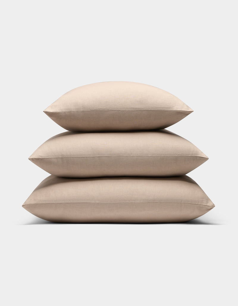 Three Cozy Earth Linen Throw Pillows in beige are stacked neatly against a plain white background.