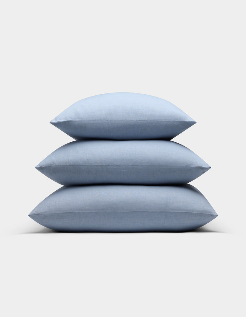 Three Cozy Earth Linen Throw Pillows in light blue are neatly stacked against a plain light gray background.