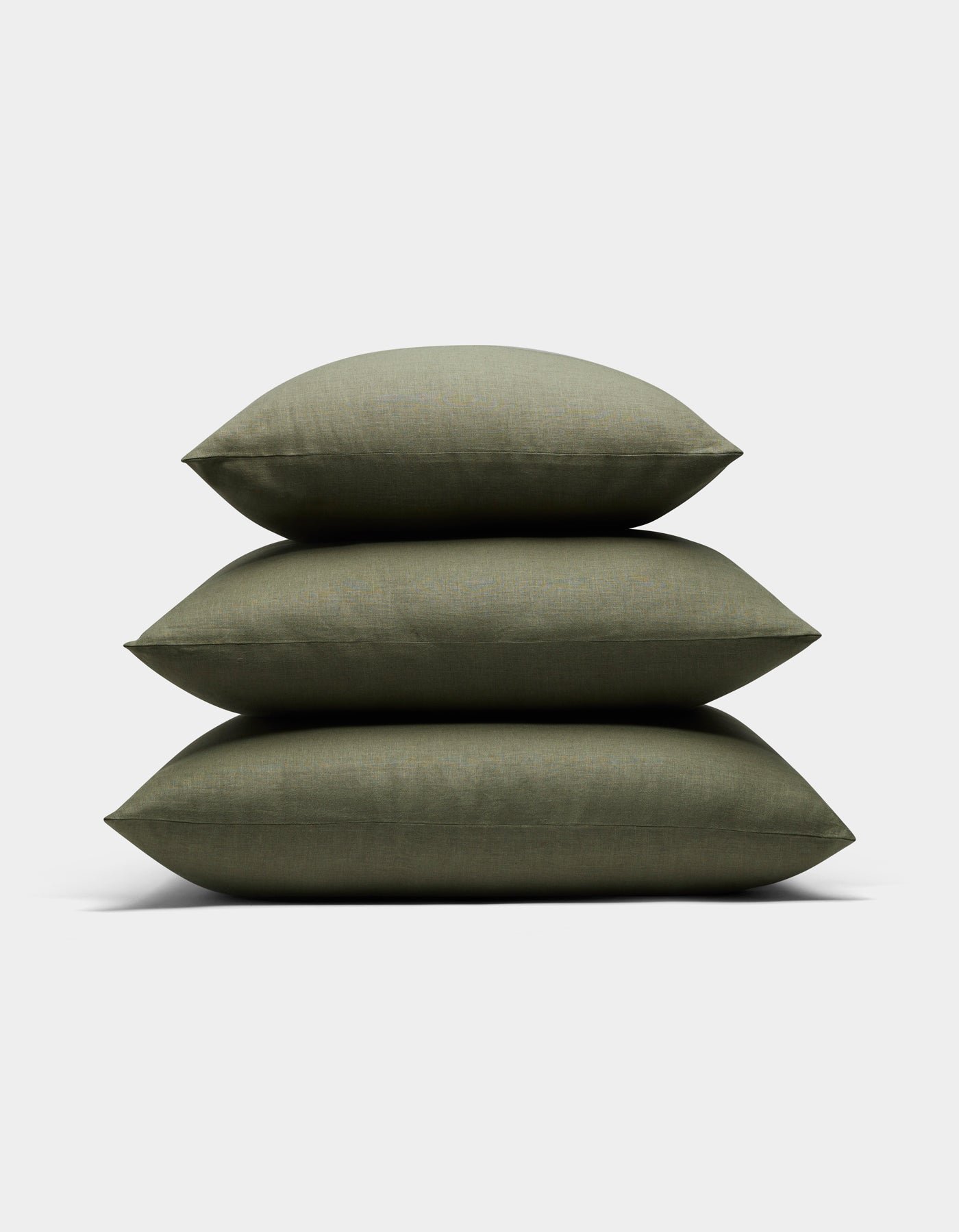 Three Cozy Earth Linen Throw Pillows in olive green are stacked neatly on top of each other against a plain white background.