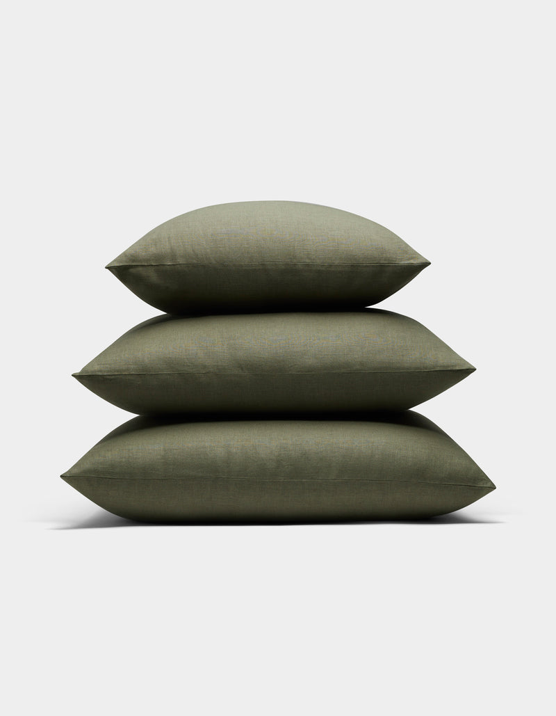 Three Cozy Earth Linen Throw Pillows in olive green are stacked neatly on top of each other against a plain white background.