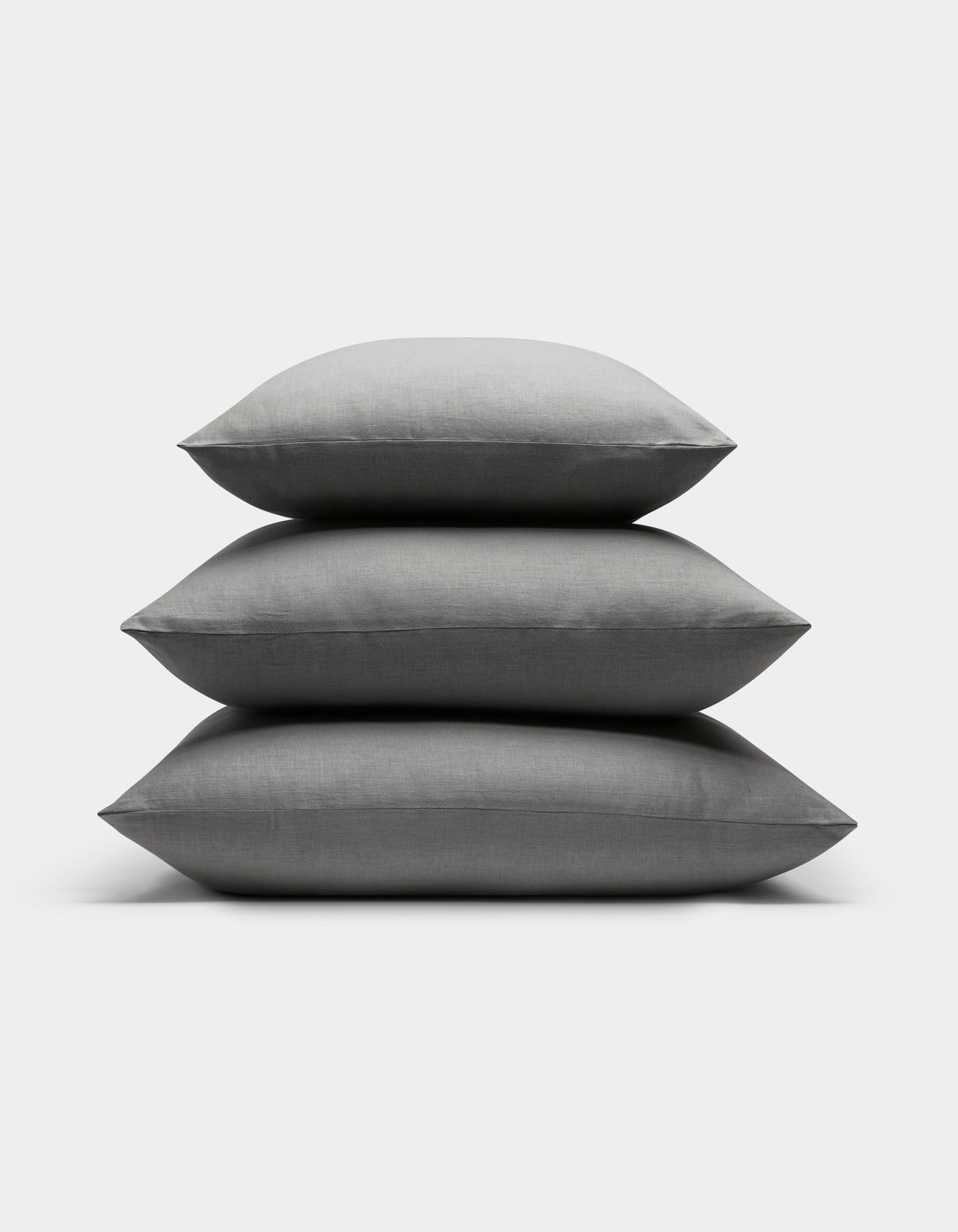 Three Cozy Earth Linen Throw Pillows are stacked neatly atop each other against a plain white background.