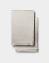 Two neatly folded Cozy Earth Silk Pillowcases in light beige are stacked together against a plain white background.|Color:Dove Grey
