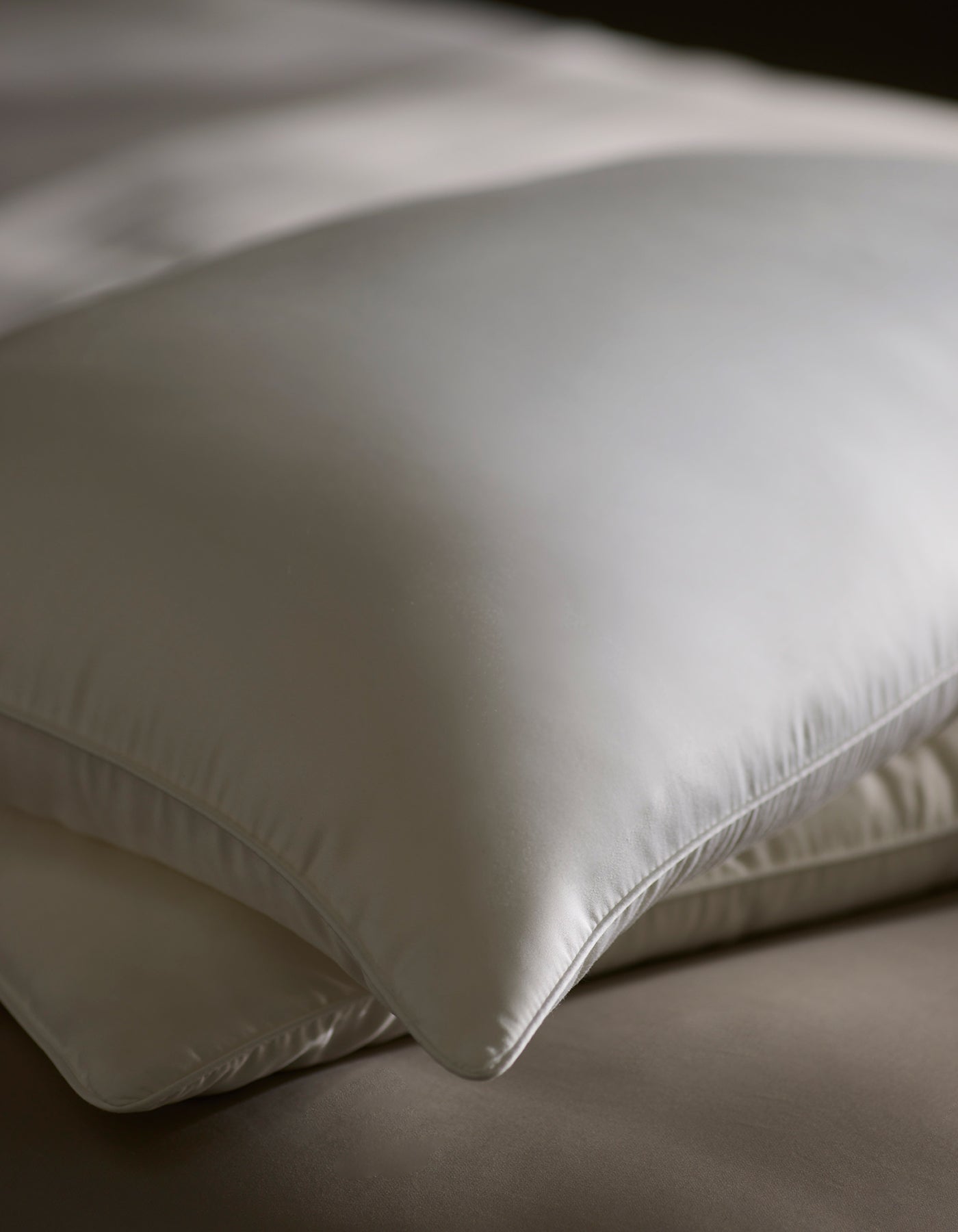Close-up of two Cozy Earth Silk Pillows, neatly stacked with a smooth, silky sheen, resting on a soft, neutral bed.