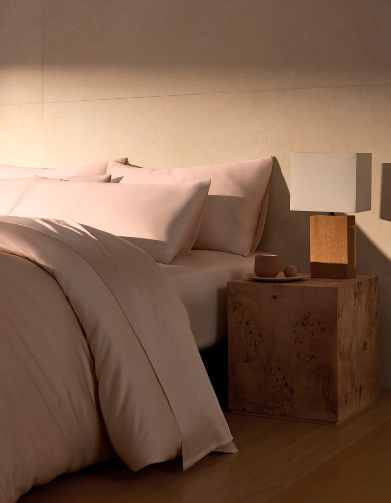 A Bamboo Duvet Cover by Cozy Earth in peony covers a cozy bed with pillows.