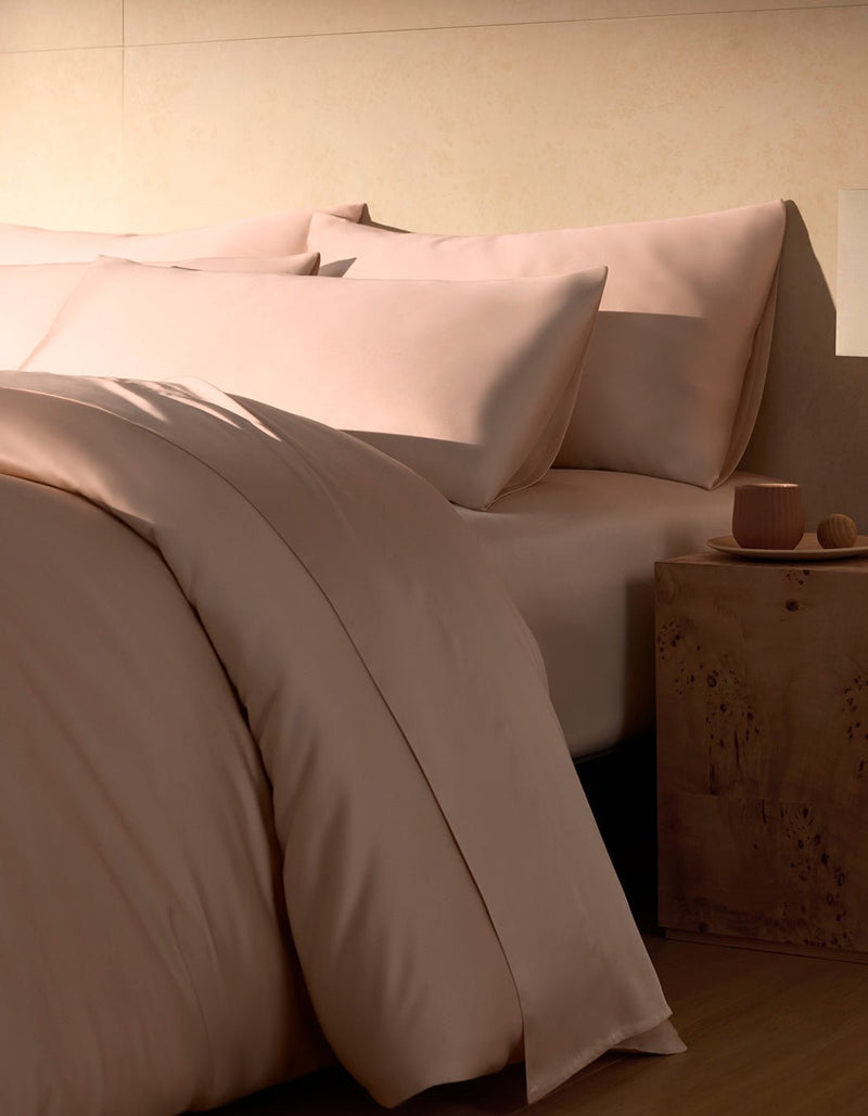 A close-up view of a neatly made bed with pink Bamboo Pillowcases by Cozy Earth, featuring a smooth, soft-looking fabric.