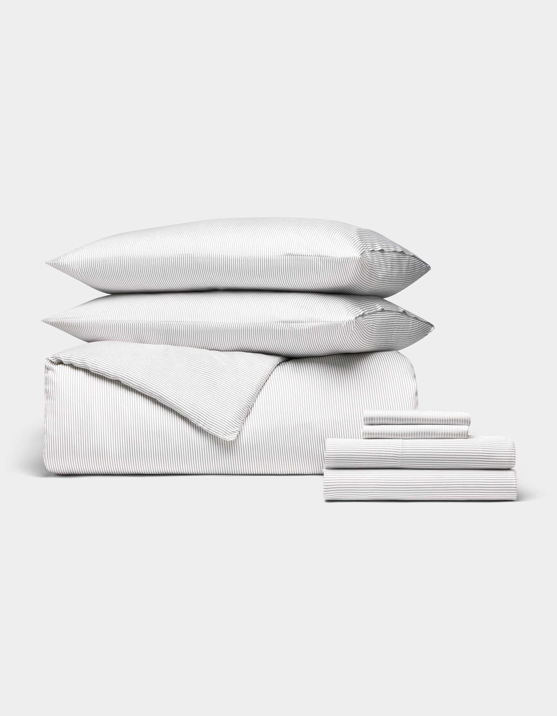 The Cozy Earth Bamboo Bedding Ultimate Bundle is neatly folded with thin gray and white stripes, featuring two pillows, a duvet, and sheets, all arranged against a plain white background.