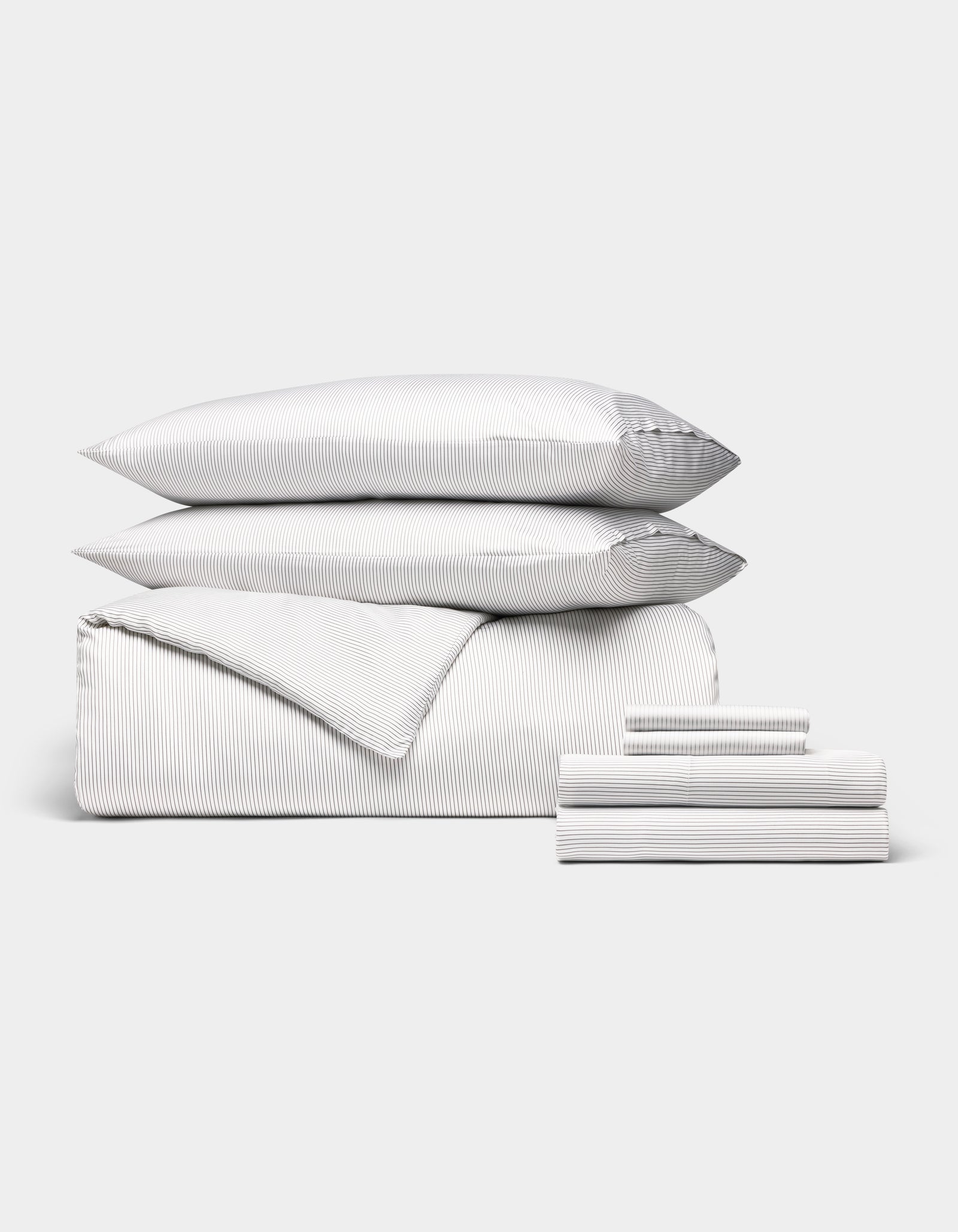 The Cozy Earth Bamboo Bedding Ultimate Bundle is neatly folded with thin gray and white stripes, featuring two pillows, a duvet, and sheets, all arranged against a plain white background.