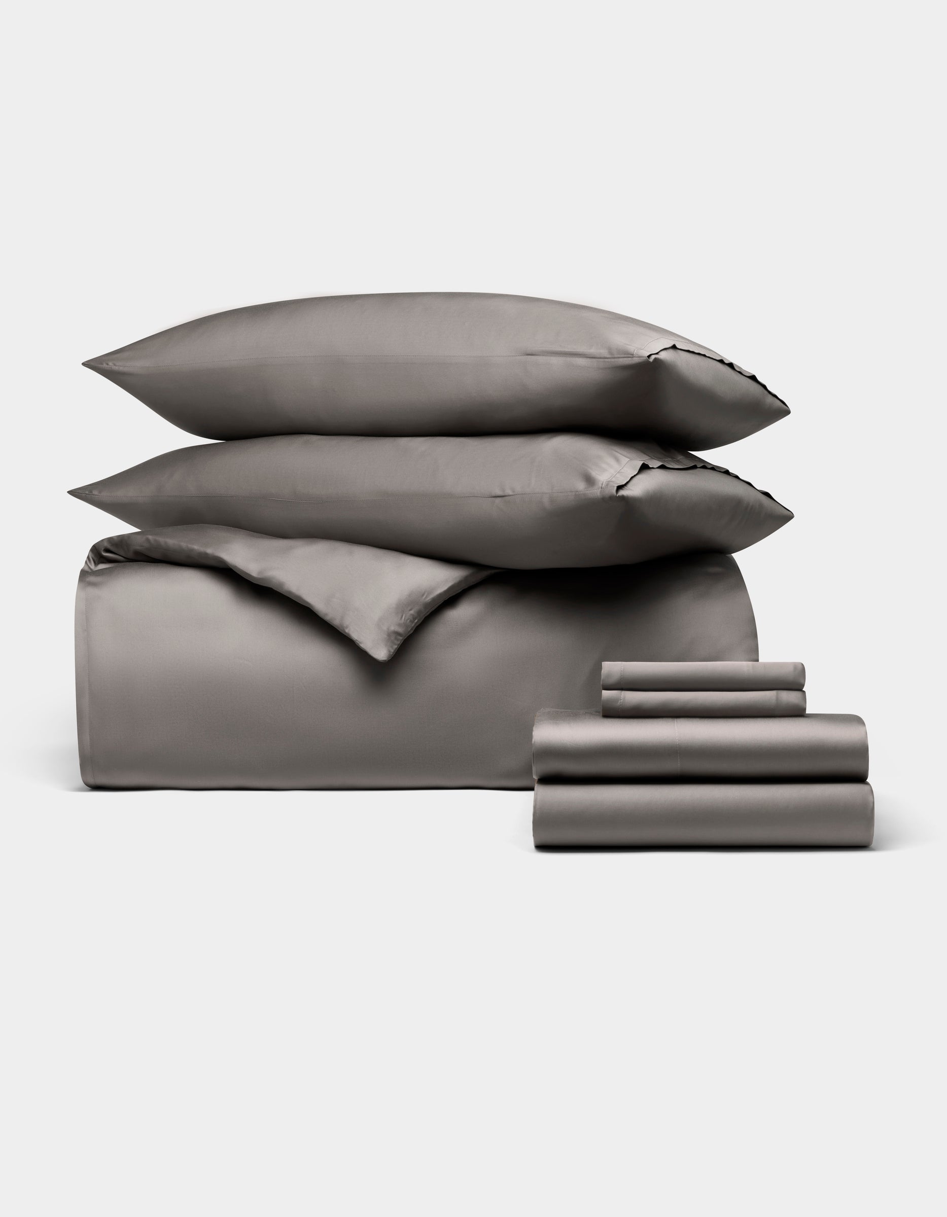 The Cozy Earth Bamboo Bedding Ultimate Bundle includes gray bed sheets, two pillows, a folded duvet, and sheets, all neatly arranged against a plain white background.
