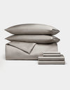 The Bamboo Bedding Ultimate Bundle by Cozy Earth features neatly stacked gray bed linens, including two pillows, a duvet, and folded sheets, all displayed against a plain white background.|Color:Dove Grey