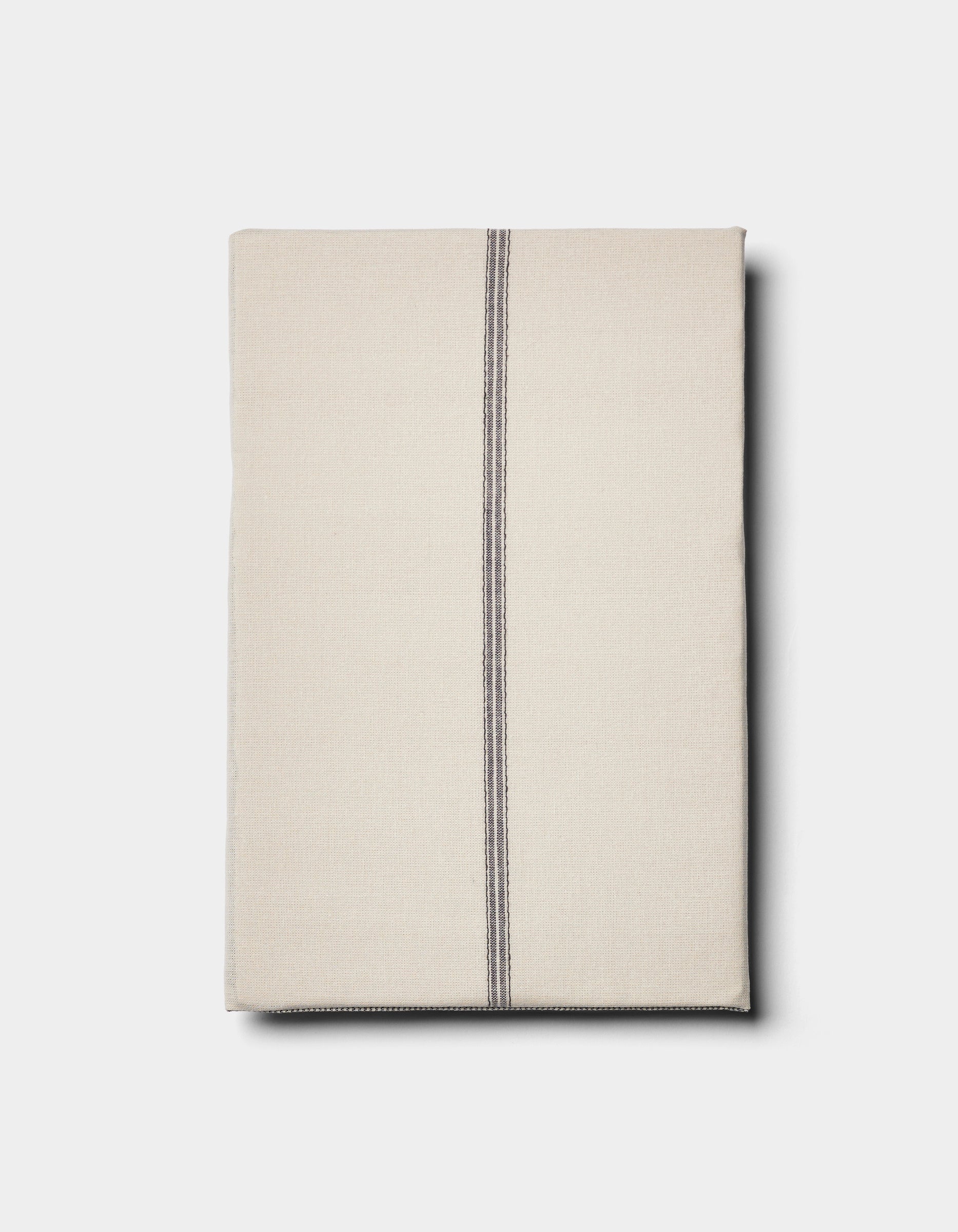 The Cozy Earth Baja Double Sided Sham is shown neatly folded in beige, featuring a single off-center vertical black stripe, set against a plain light background.