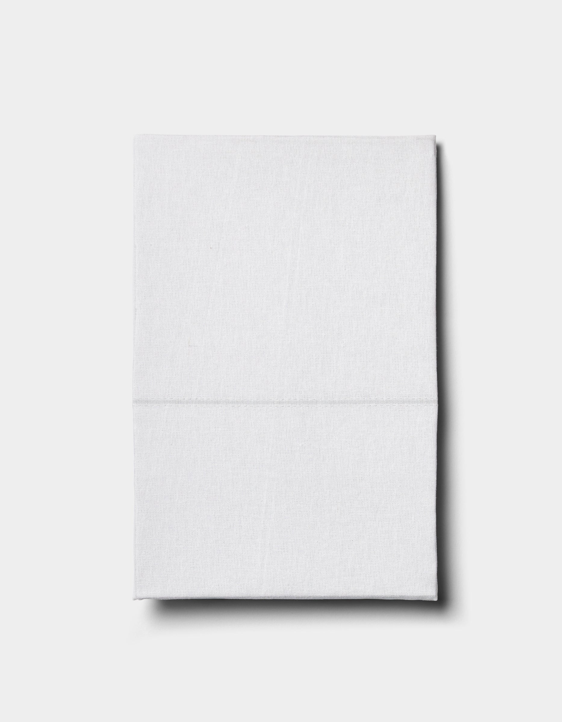 The Baja Double Sided Sham by Cozy Earth, neatly folded, rests on a plain light gray surface and casts a subtle shadow to the right.