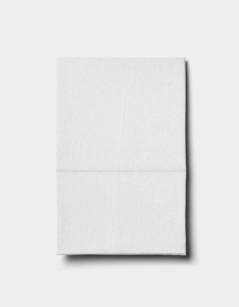 The Baja Double Sided Sham by Cozy Earth, neatly folded, rests on a plain light gray surface and casts a subtle shadow to the right.