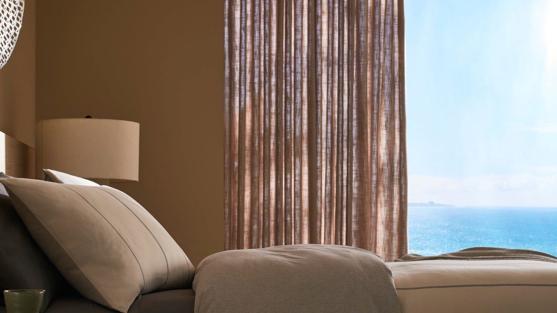 Beige sofa with a lamp and view of the ocean through a window.