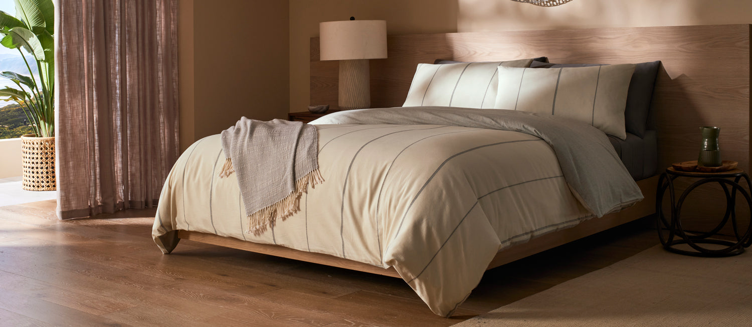 Neatly made bed with Cozy Earth Baja bedding in a bedroom setting.