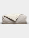 The Baja Duvet Cover by Cozy Earth, in light beige, is shown with a cream-colored blanket draped diagonally over it against a plain, light background.|Color:Coal Stripe/Striped Alabaster