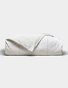 The Baja Duvet Cover by Cozy Earth is neatly folded with a slightly rumpled corner, set against a plain light gray background.|Color:Laurel Stripe/Striped Bone
