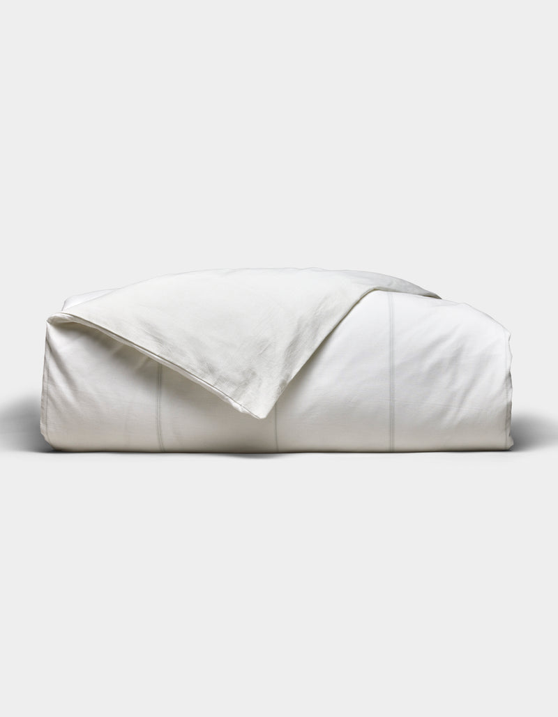 The Baja Duvet Cover by Cozy Earth is neatly folded with a slightly rumpled corner, set against a plain light gray background.