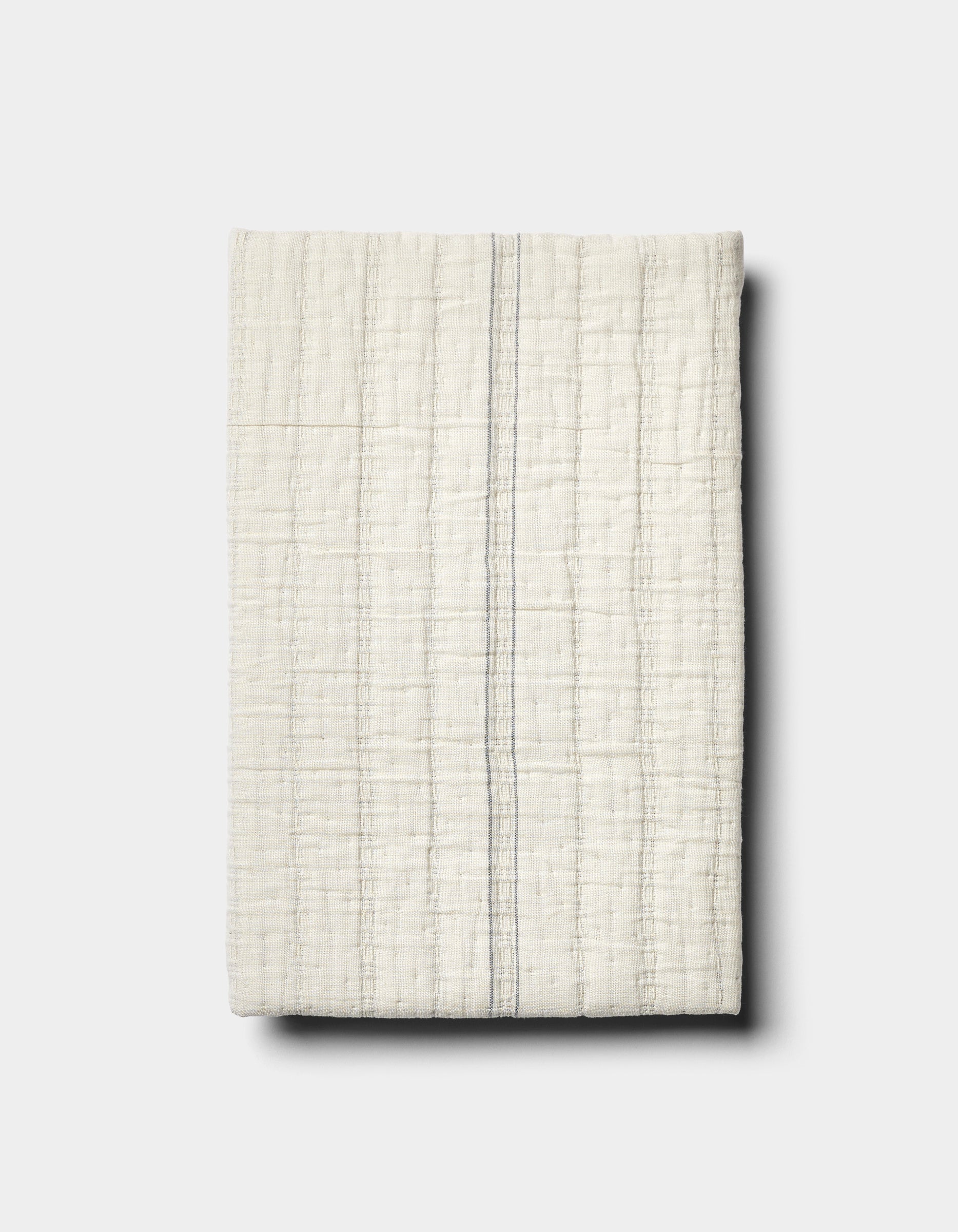 The Baja Matelasse Sham by Cozy Earth features off-white textured fabric with a subtle grid pattern and a single thin grey vertical stripe, displayed on a light grey background.
