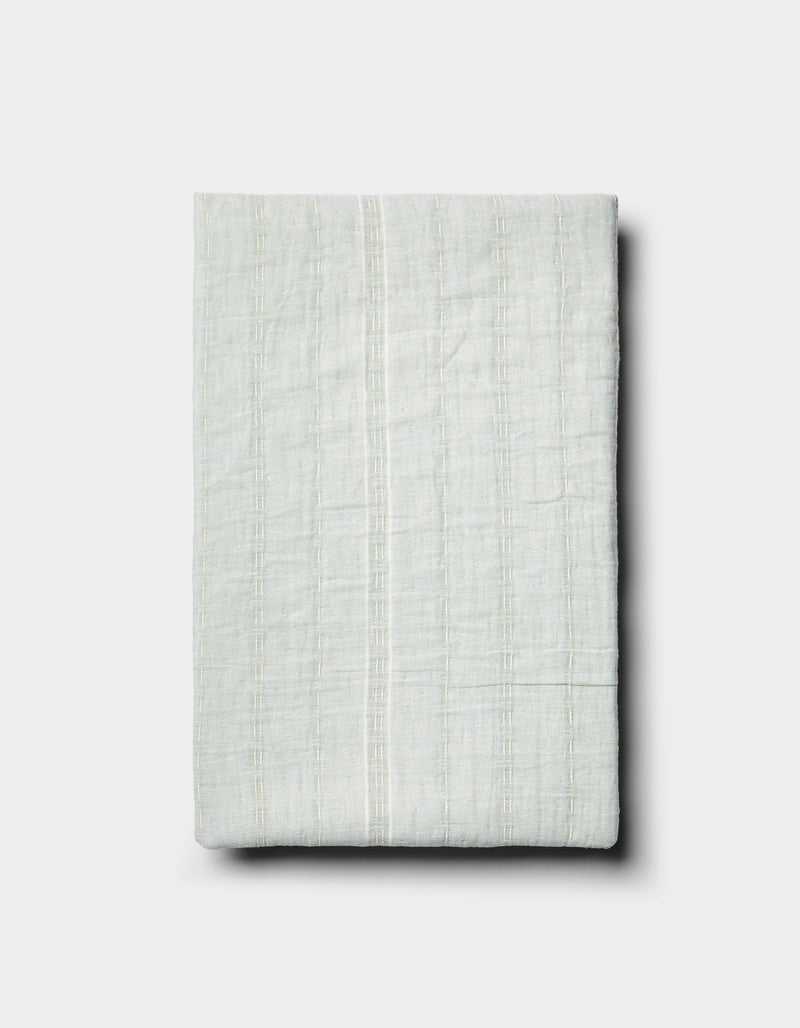 The Baja Matelasse Sham by Cozy Earth is a neatly folded, light-colored textured fabric with subtle vertical stripes, displayed on a plain white background.