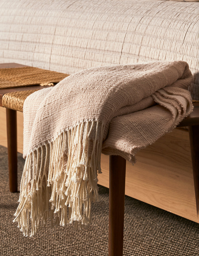 Cozy Earth Baja Throw blanket is draped across a bench at the foot of a bed.