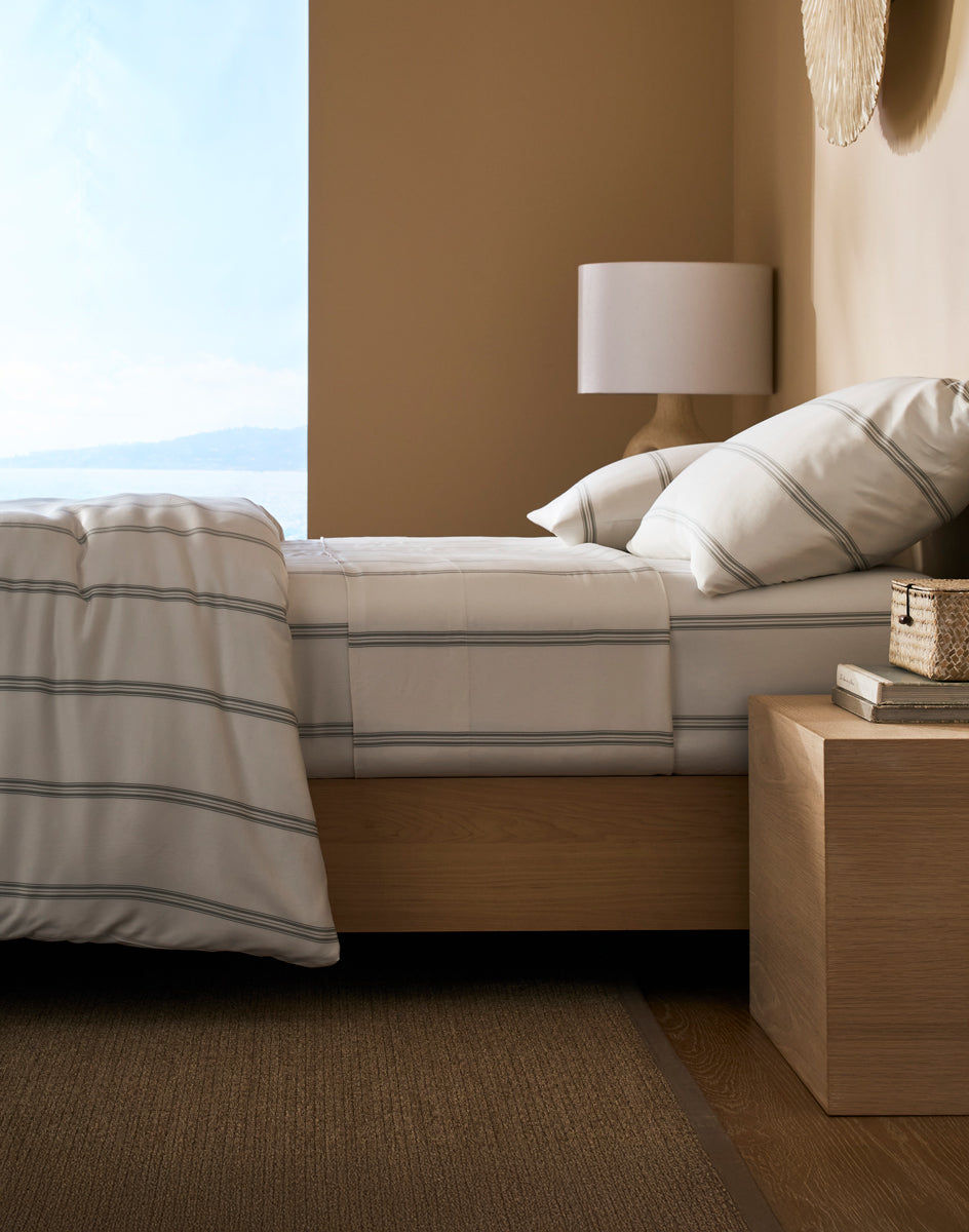 Bedroom with Cozy Earth Baja Stripe Bamboo bedding and a lamp on a nightstand.
