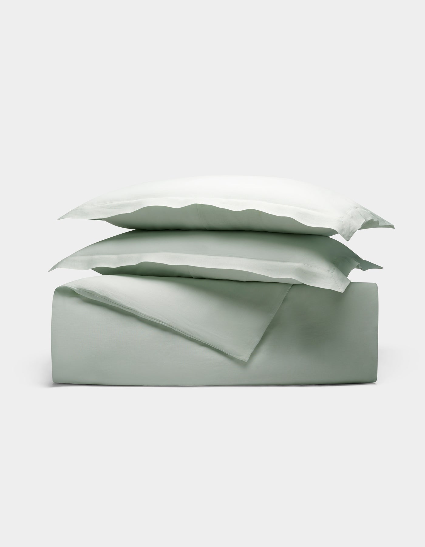 The Cozy Earth Linen Duvet Set in sage green features a neatly folded duvet and two stacked pillowcases, all showcased against a plain white background.|Color:Mist
