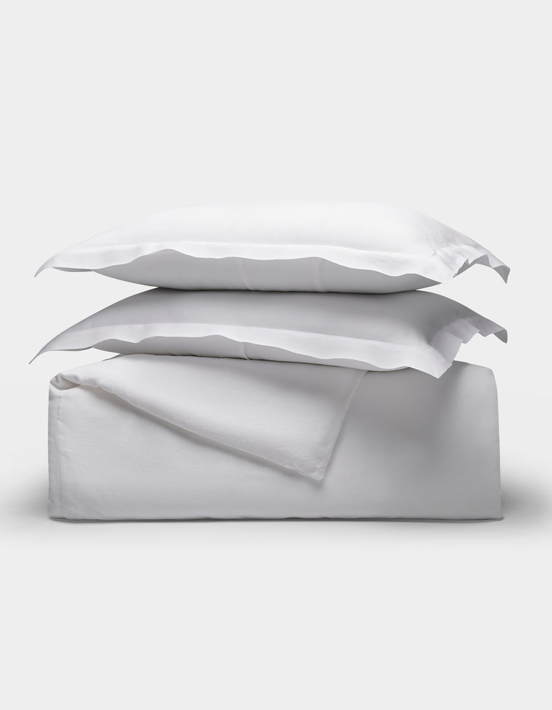 The Linen Duvet Set by Cozy Earth is shown neatly folded with two stacked pillows, arranged on top of folded sheets against a plain light background.