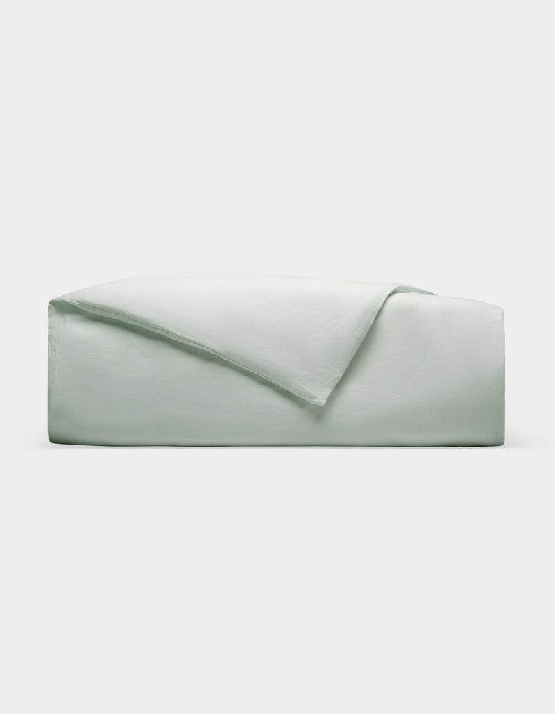 A Cozy Earth Linen Duvet Cover, neatly folded in light gray or pale green, is stacked on a plain white background.