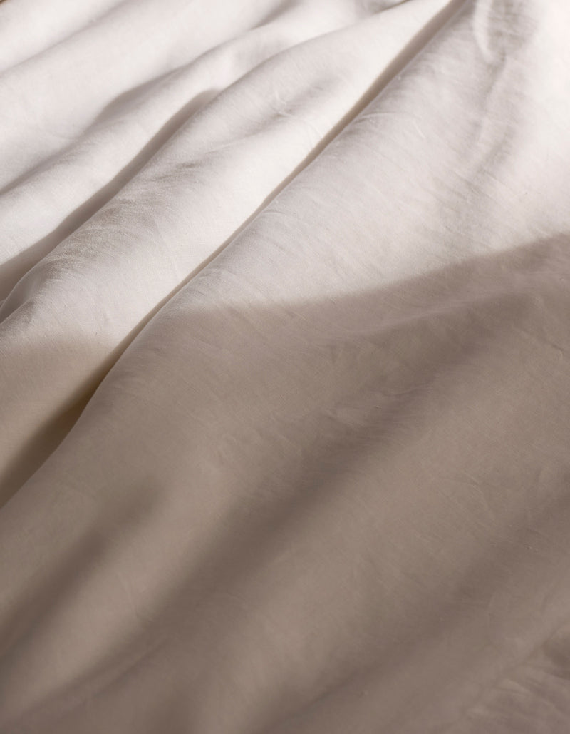 Soft sunlight casts gentle shadows across the Cozy Earth Linen Duvet Cover, its light-hued fabric creating a calm and cozy atmosphere.
