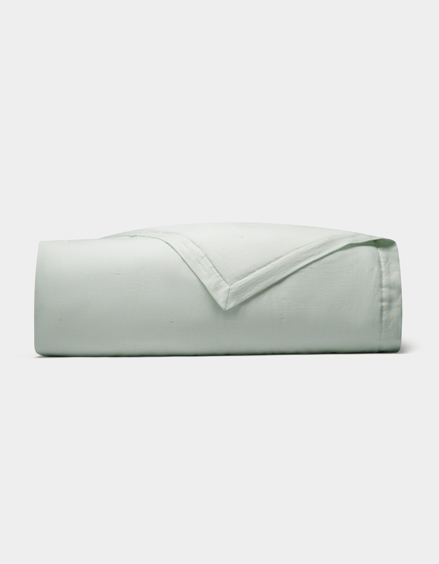 The Cozy Earth Linen Quilt, in a light green shade, is neatly folded and displayed against a plain white background.|Color:Mist
