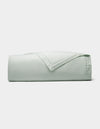 The Cozy Earth Linen Quilt, in a light green shade, is neatly folded and displayed against a plain white background.|Color:Mist