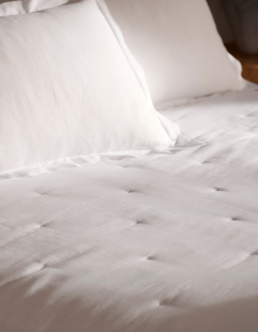 A close-up of a neatly made bed featuring the Cozy Earth Linen Quilt, paired with white pillows for a clean, soft, and inviting look. 
