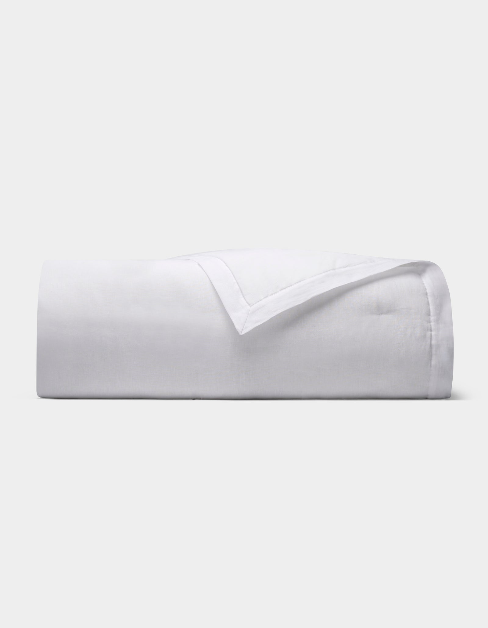 The Cozy Earth Linen Quilt, featuring a smooth texture, is neatly folded and displayed against a plain light gray background.