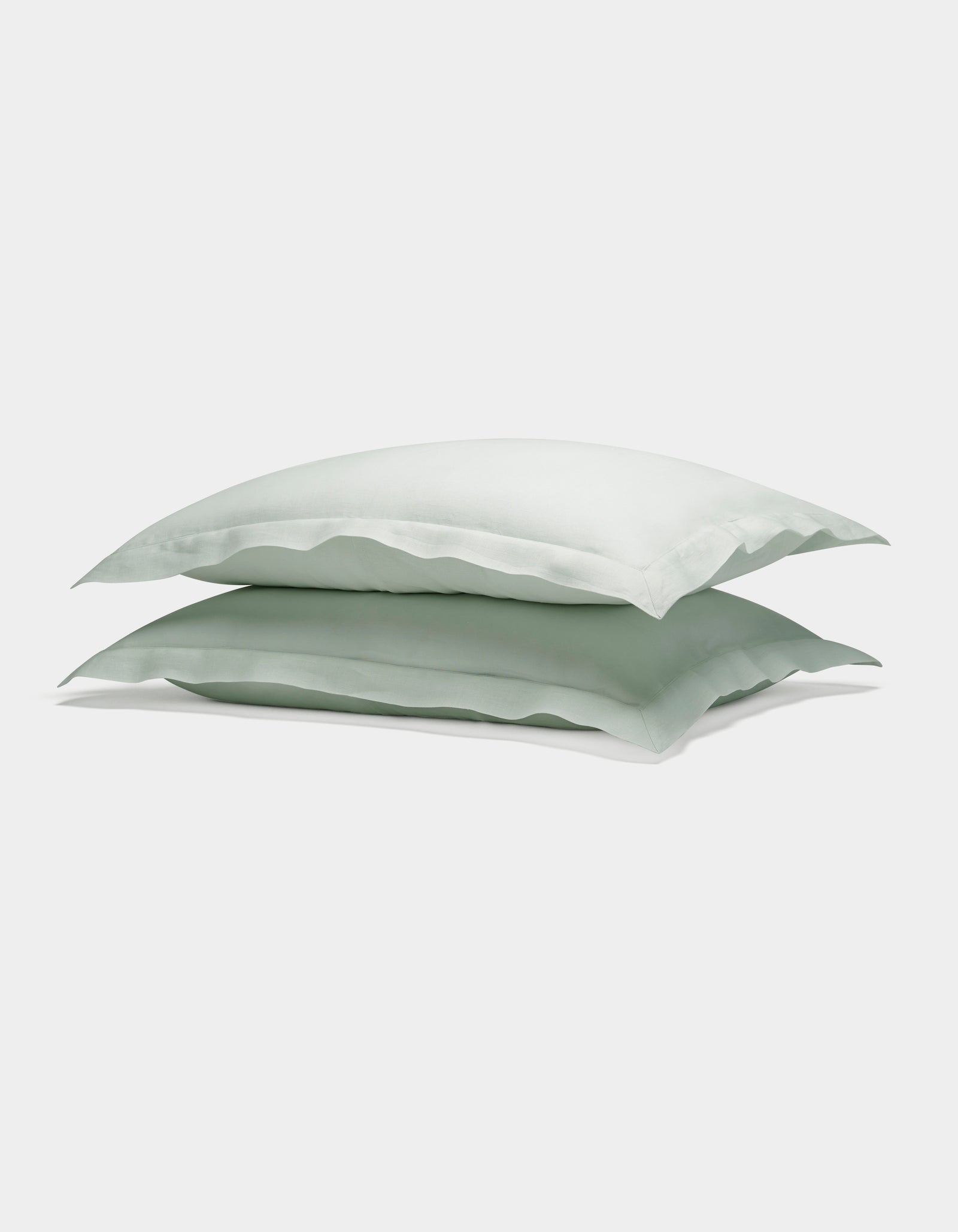 Two Cozy Earth Linen Shams in light green are neatly stacked atop each other against a plain white background.