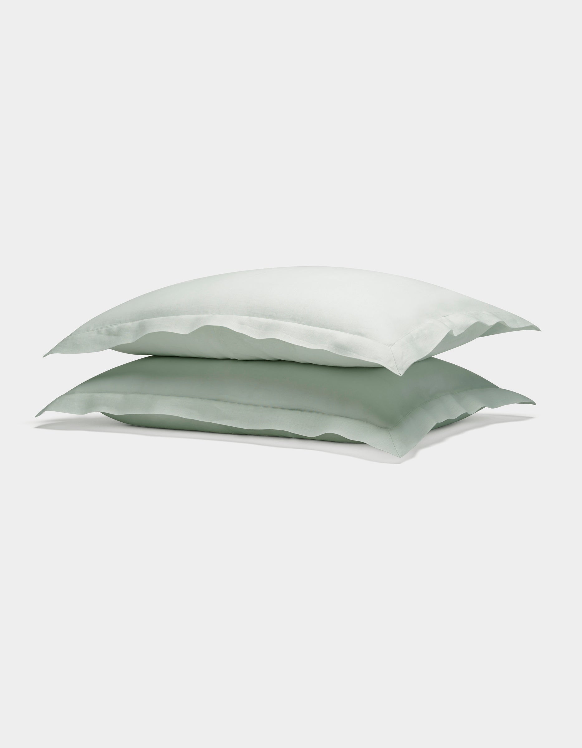 Two Cozy Earth Linen Shams in light green are neatly stacked atop each other against a plain white background.
