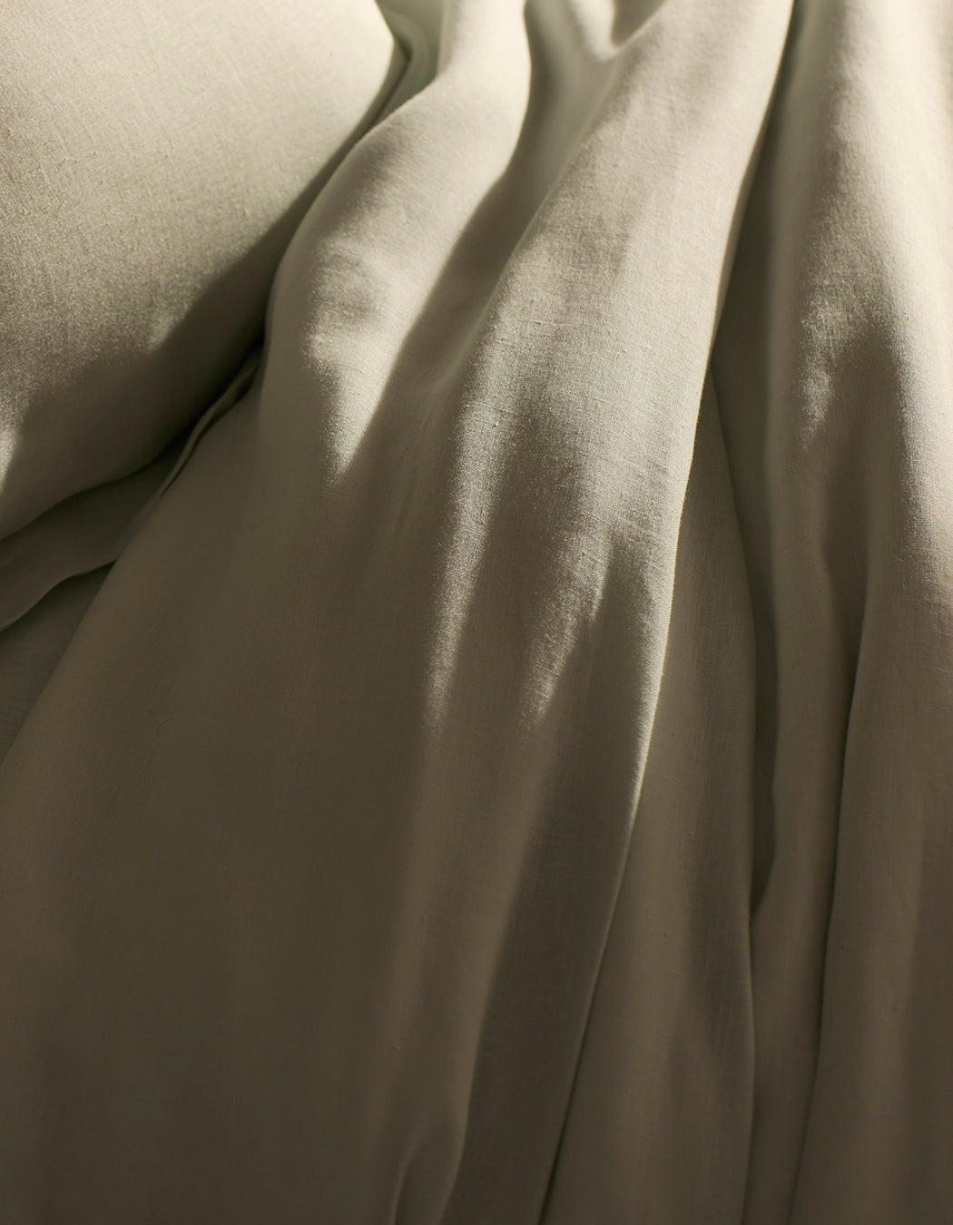 A close-up of Cozy Earth’s Linen Duvet Cover shows soft, beige fabric with gentle folds and a smooth, slightly wrinkled texture, creating a calm and cozy atmosphere—perfect for a relaxing bedroom.