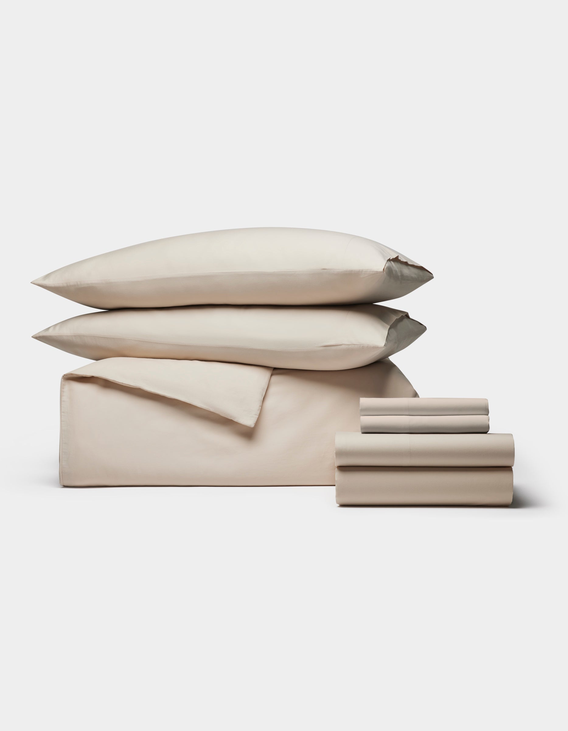 The Cozy Earth Soft-Wash Cotton Bedding Core Bundle features beige sheets, a flat sheet, two pillowcases, and two pillows, all neatly stacked and displayed against a plain white background.|Color:Driftwood