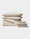 The Cozy Earth Soft-Wash Cotton Bedding Core Bundle features beige sheets, a flat sheet, two pillowcases, and two pillows, all neatly stacked and displayed against a plain white background.|Color:Driftwood