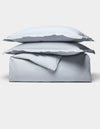 The Cozy Earth Soft-Wash Cotton Duvet Bundle features a neatly folded light gray set, including two stacked pillows and a duvet, displayed on a plain white background.|Color:Shore