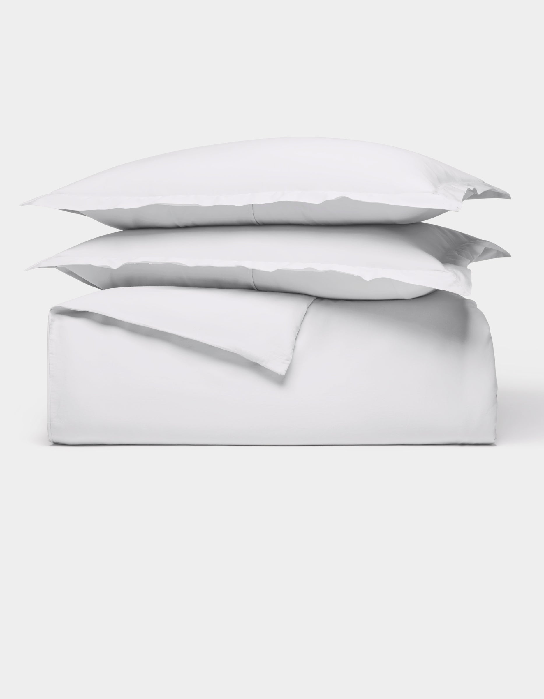 The Cozy Earth Soft-Wash Cotton Duvet Bundle features a neatly folded white sheet set with two stacked pillows, all displayed against a plain white background.