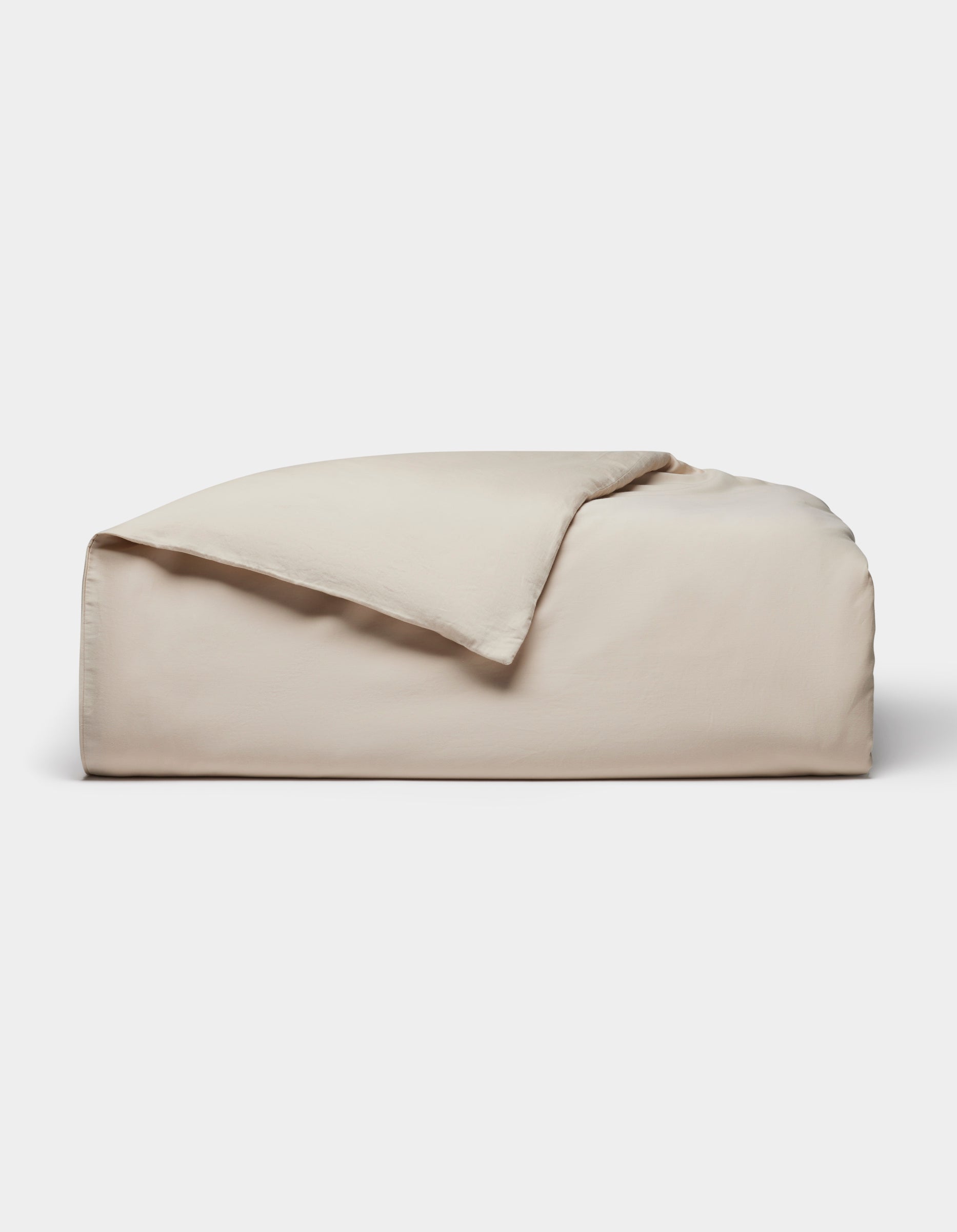 The Cozy Earth Soft-Wash Cotton Duvet Cover, in light beige, is neatly folded with one corner partially flipped over and displayed against a plain white background.|Color:Driftwood