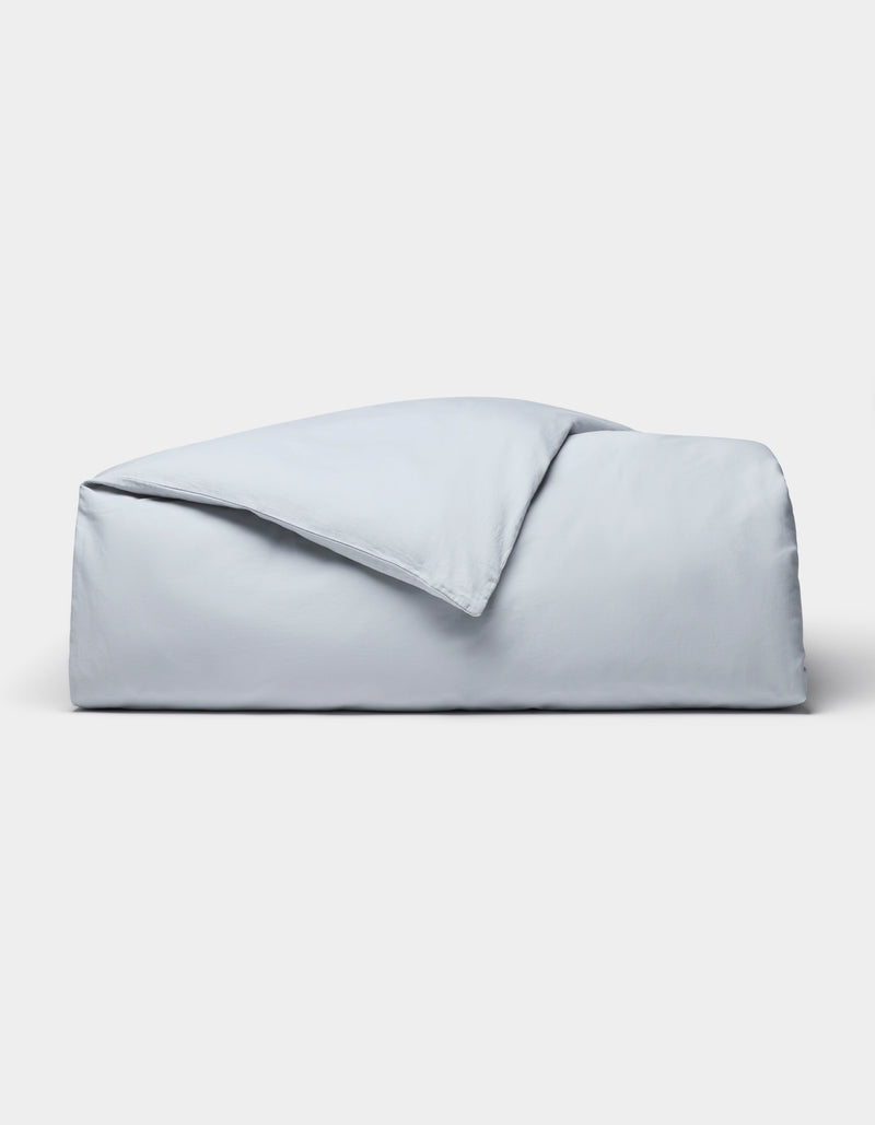 The Cozy Earth Soft-Wash Cotton Duvet Cover set, in light blue, is neatly folded and displayed against a plain white background.