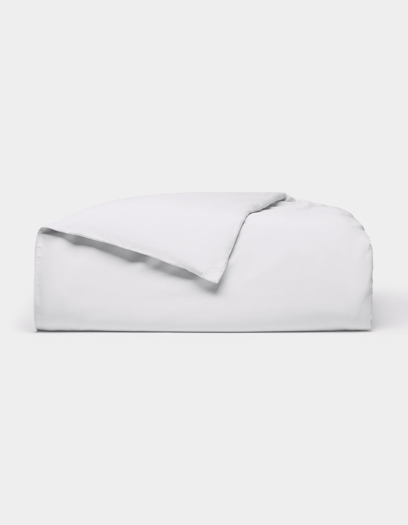 The Cozy Earth Soft-Wash Cotton Duvet Cover, in white, is neatly folded on a white background with one corner flipped over to show the inside.