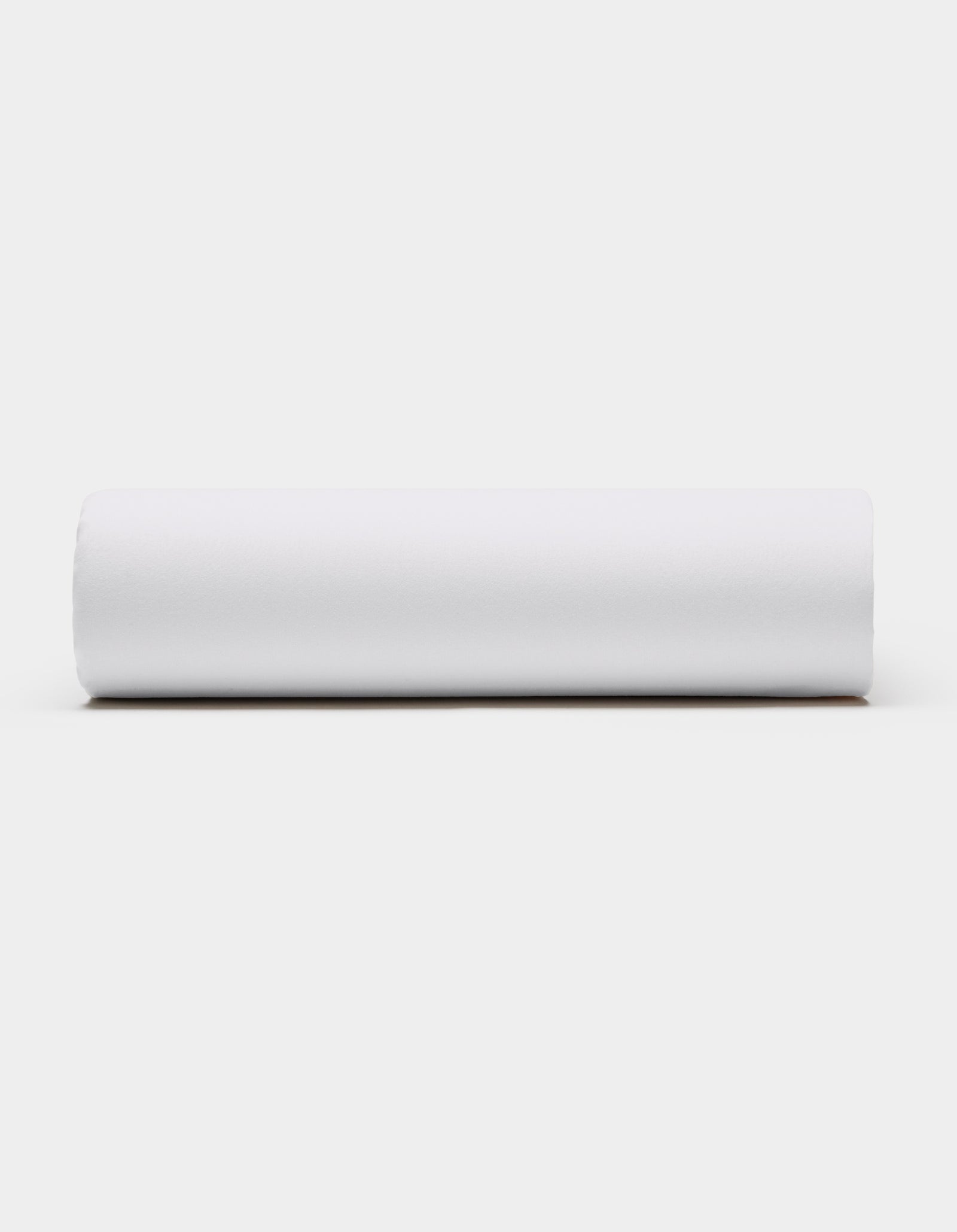 A Soft-Wash Cotton Fitted Sheet by Cozy Earth, in plain white, is displayed horizontally against a light gray background, viewed from the side.