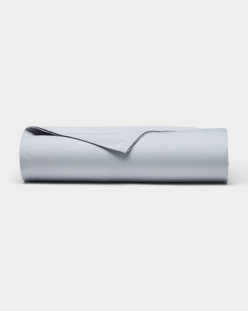 The Cozy Earth Soft-Wash Cotton Flat Sheet, shown neatly rolled with one edge lifted, is displayed against a plain white background.