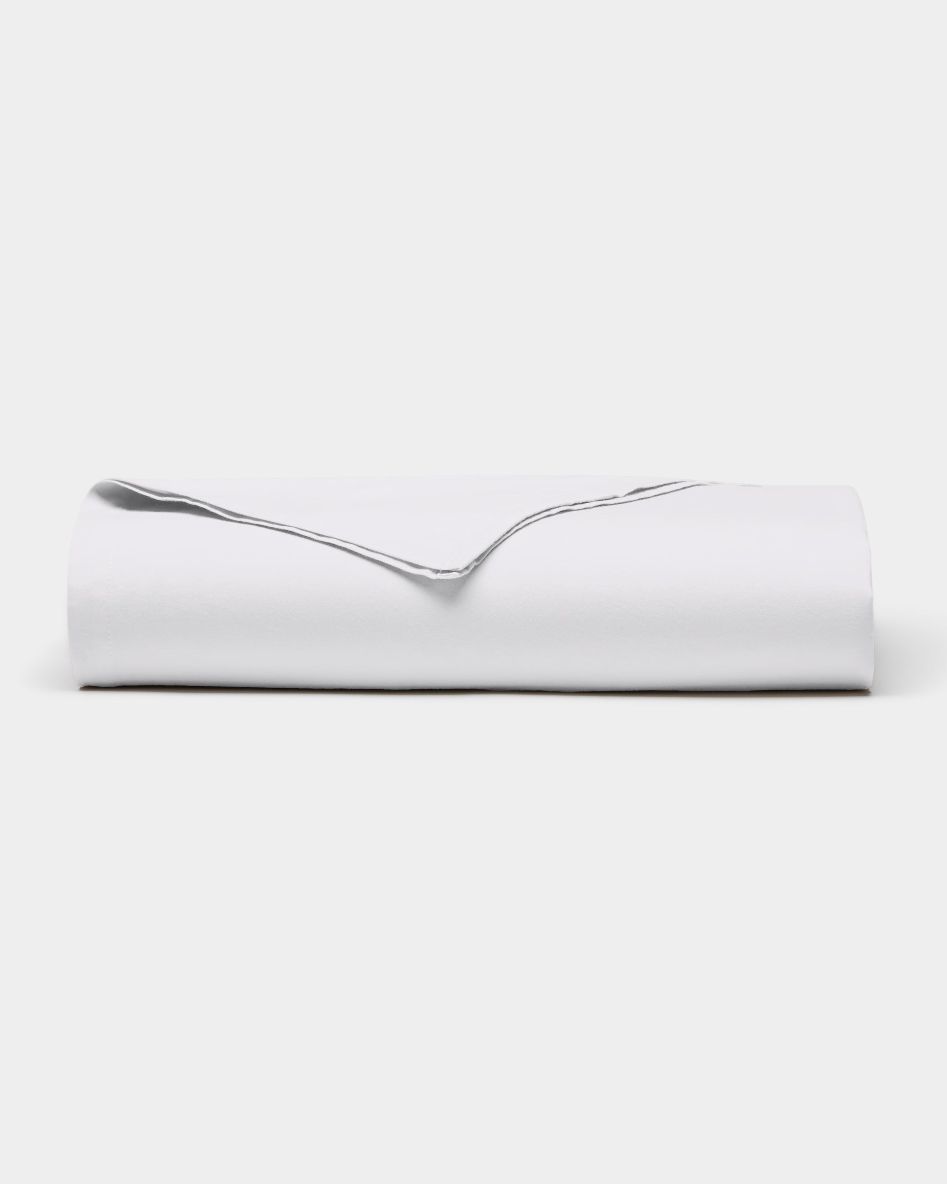 A neatly folded Soft-Wash Cotton Sheet Set by Cozy Earth, featuring a visible edge, is placed on a plain white background.